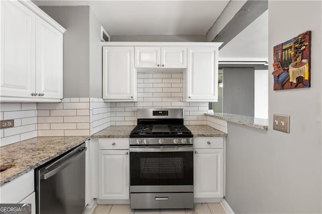 kitchen with light stone counters, appliances with stainless steel finishes, backsplash, and white cabinetry