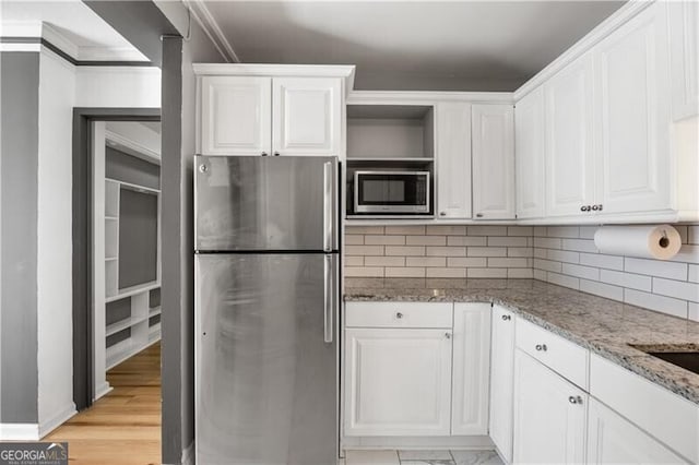 kitchen with white cabinets, decorative backsplash, appliances with stainless steel finishes, light stone counters, and open shelves