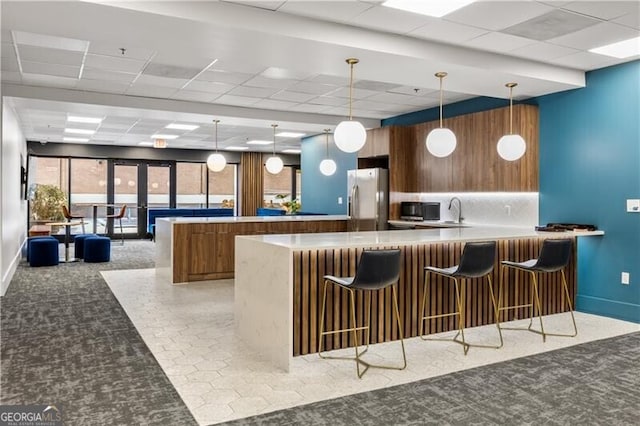 kitchen featuring a peninsula, carpet floors, backsplash, modern cabinets, and stainless steel fridge