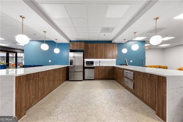 kitchen with a drop ceiling, stainless steel appliances, a peninsula, light countertops, and light floors