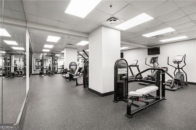 workout area featuring a paneled ceiling, visible vents, and baseboards