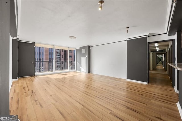 unfurnished living room featuring a wall of windows and light wood-type flooring