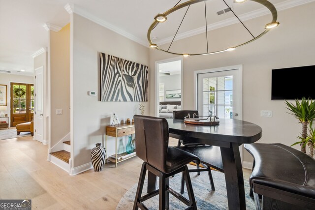 dining area with light wood-type flooring, a healthy amount of sunlight, and crown molding