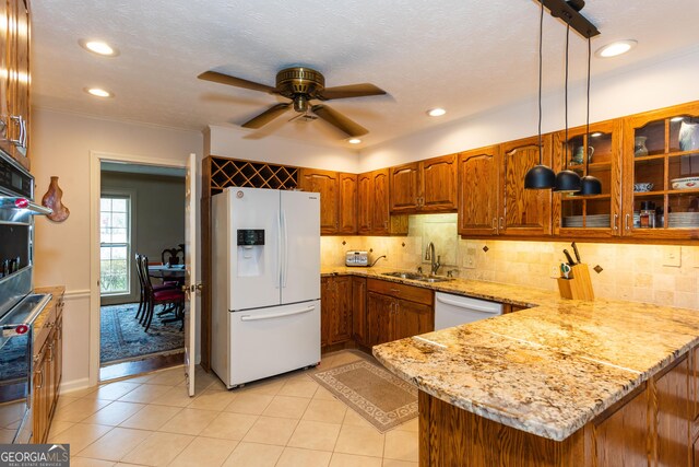 kitchen with light stone countertops, pendant lighting, dishwasher, and sink