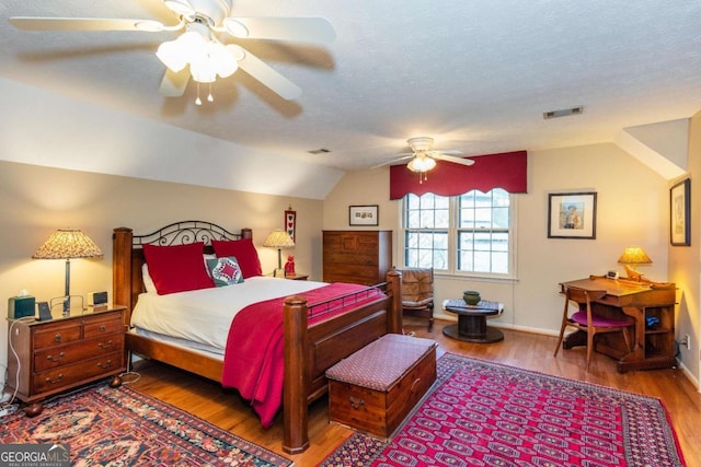 bedroom featuring ceiling fan, wood-type flooring, a textured ceiling, and vaulted ceiling