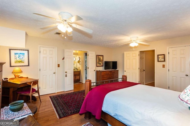 bedroom with a baseboard radiator, a textured ceiling, hardwood / wood-style floors, ensuite bath, and ceiling fan