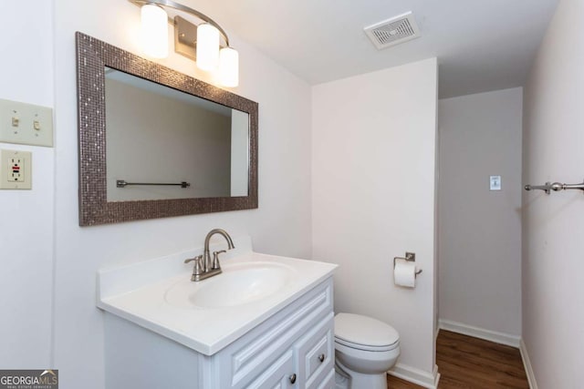 bathroom featuring toilet, vanity, and hardwood / wood-style flooring