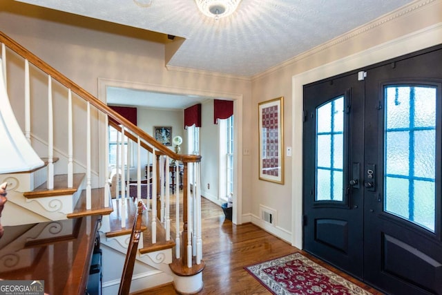 foyer featuring hardwood / wood-style floors, ornamental molding, and french doors