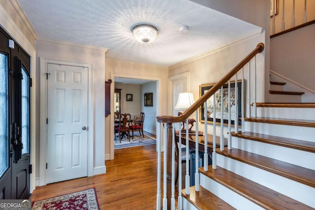 entrance foyer with hardwood / wood-style flooring, a textured ceiling, and crown molding