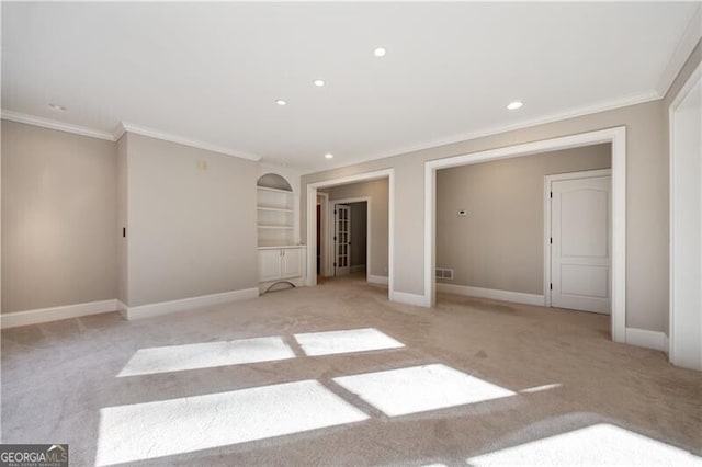 unfurnished room with crown molding, built in features, and light carpet