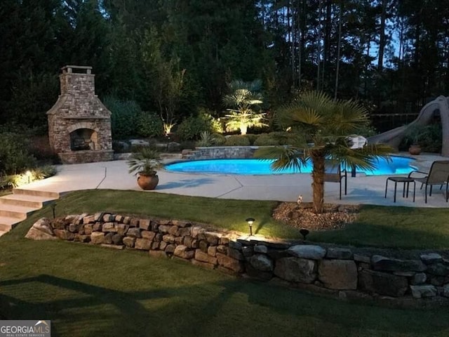 view of pool with exterior fireplace, a patio area, a lawn, and a water slide