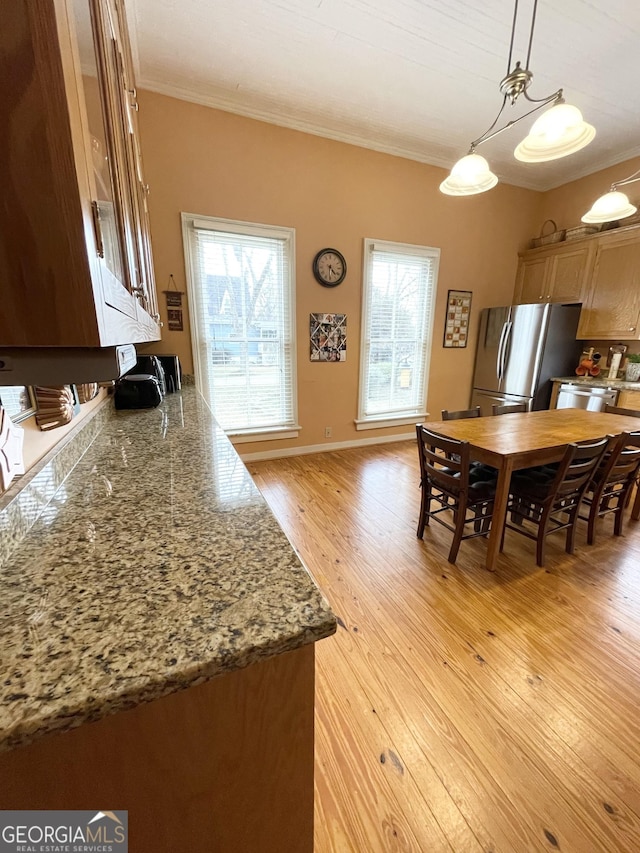 kitchen featuring stainless steel appliances, pendant lighting, light hardwood / wood-style floors, and ornamental molding