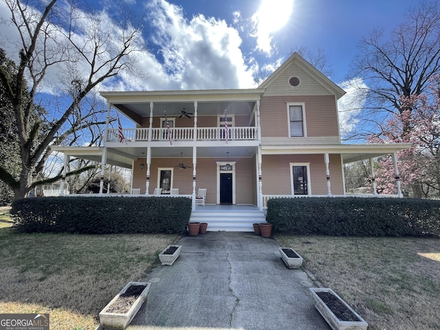 view of front of home featuring ceiling fan, a front lawn, a balcony, and a porch