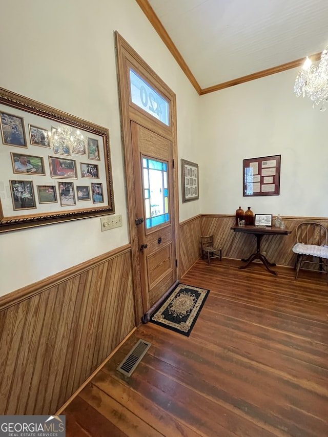 foyer entrance featuring vaulted ceiling, ornamental molding, a chandelier, and wood-type flooring