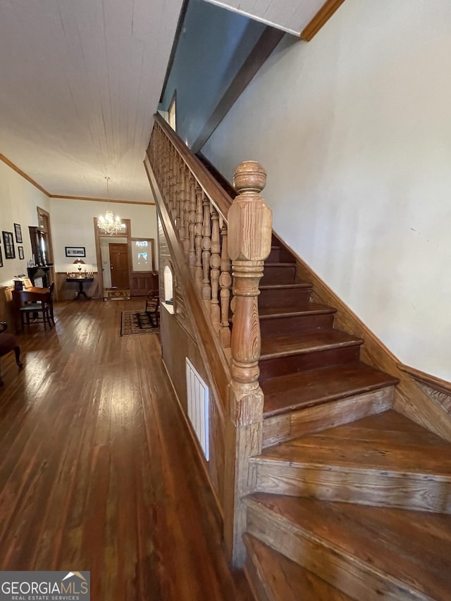 stairs featuring ornamental molding, hardwood / wood-style flooring, and a notable chandelier