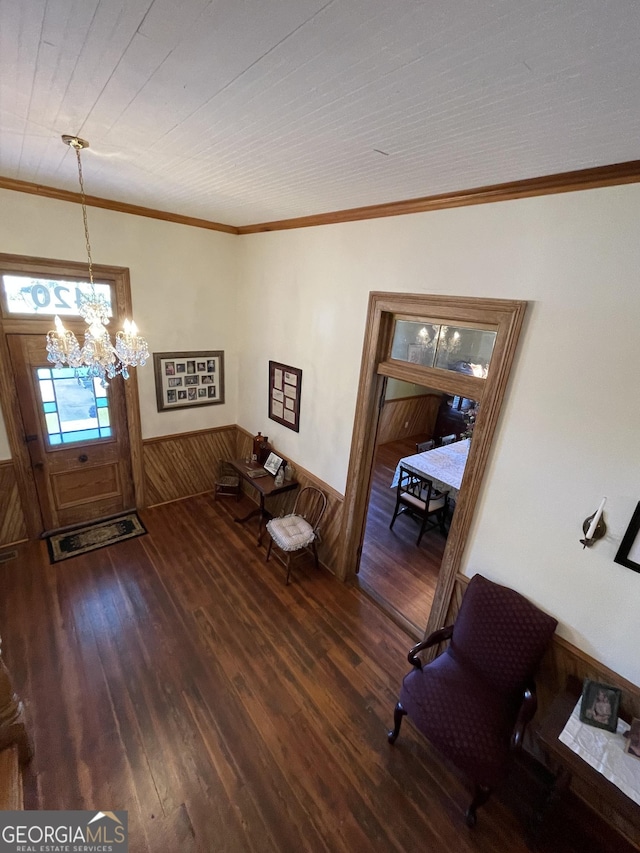 foyer featuring crown molding, dark hardwood / wood-style flooring, wood walls, and a notable chandelier