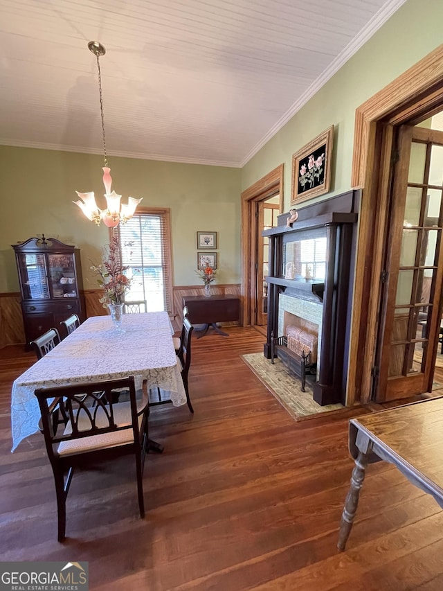 dining space featuring hardwood / wood-style flooring, wooden walls, crown molding, and an inviting chandelier