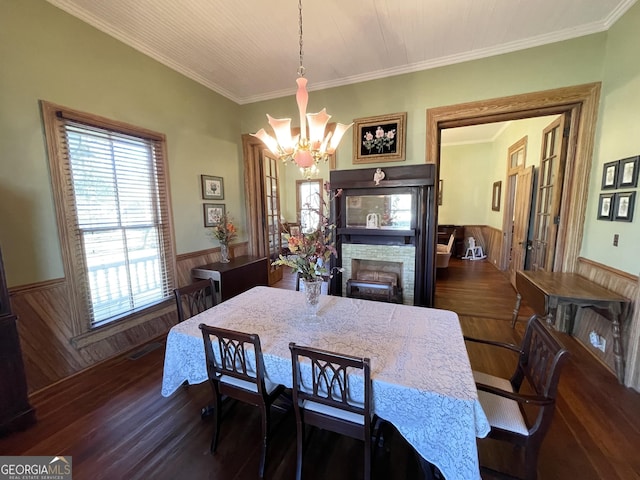 dining space featuring wood walls, dark hardwood / wood-style flooring, ornamental molding, and an inviting chandelier