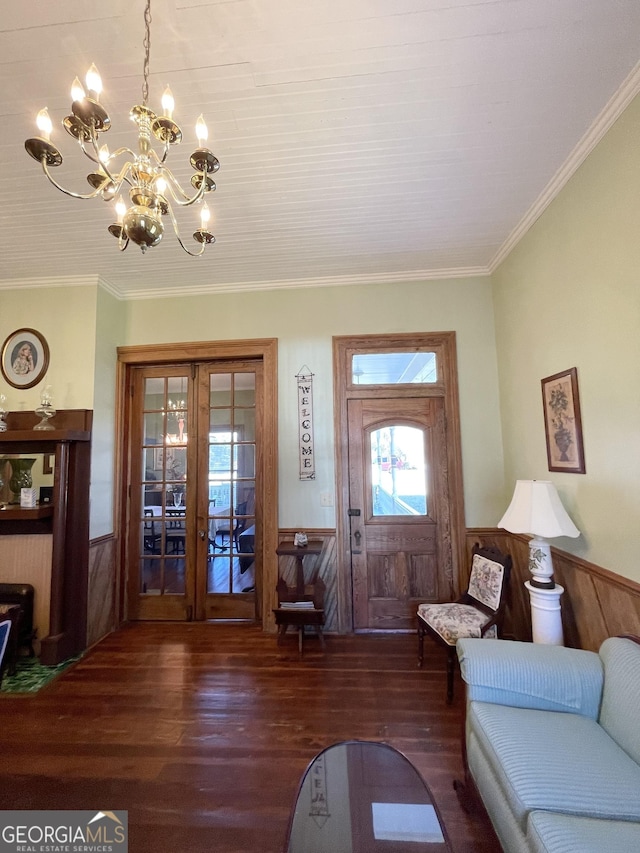 foyer featuring french doors, dark hardwood / wood-style floors, ornamental molding, and a notable chandelier