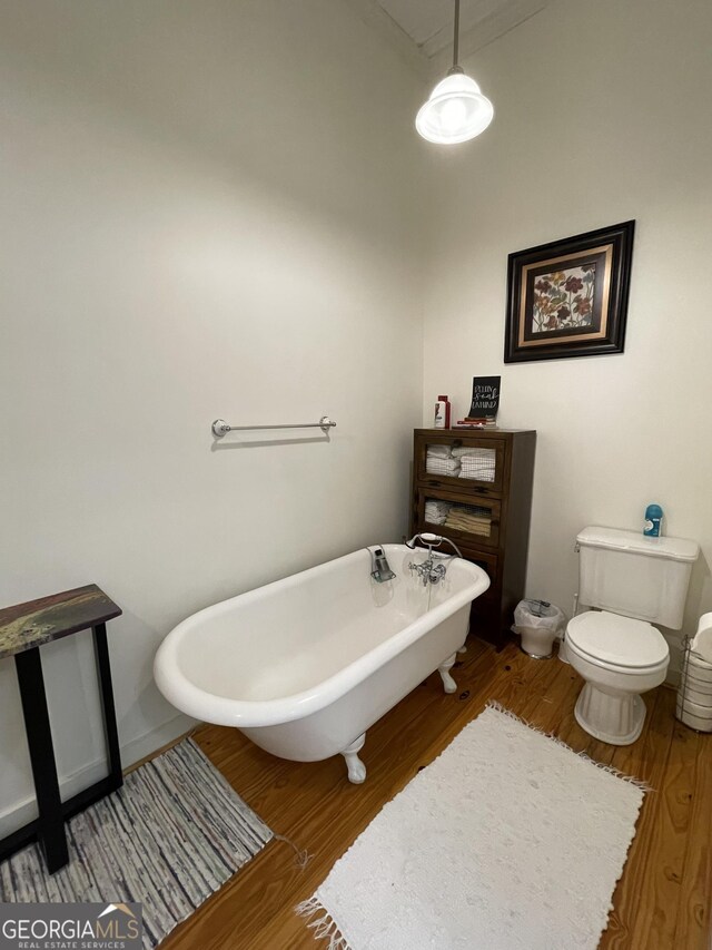 bathroom featuring a washtub, wood-type flooring, and toilet