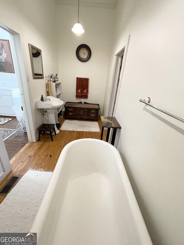 bathroom with washer / dryer, a washtub, and hardwood / wood-style floors