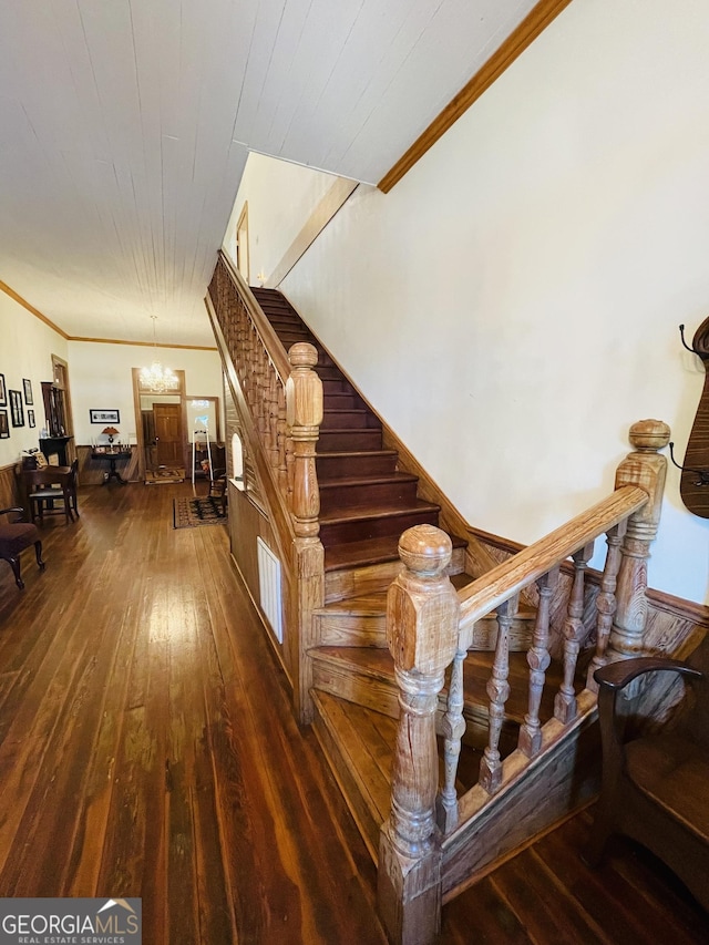 stairs featuring hardwood / wood-style floors, crown molding, and a chandelier