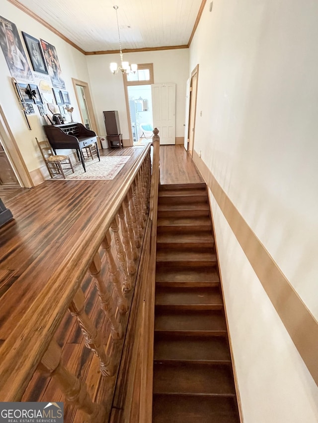 staircase with wood-type flooring, a chandelier, and ornamental molding