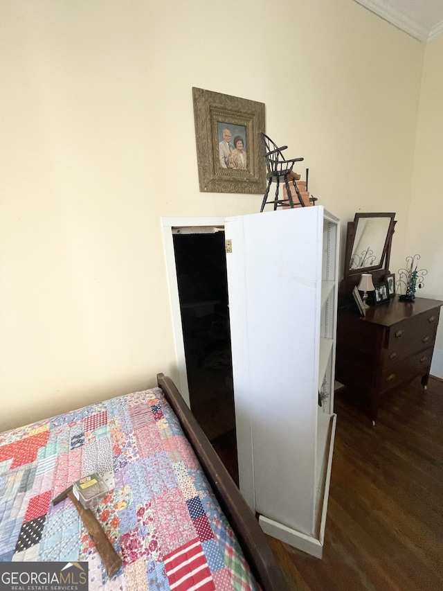 bedroom with dark hardwood / wood-style floors and ornamental molding