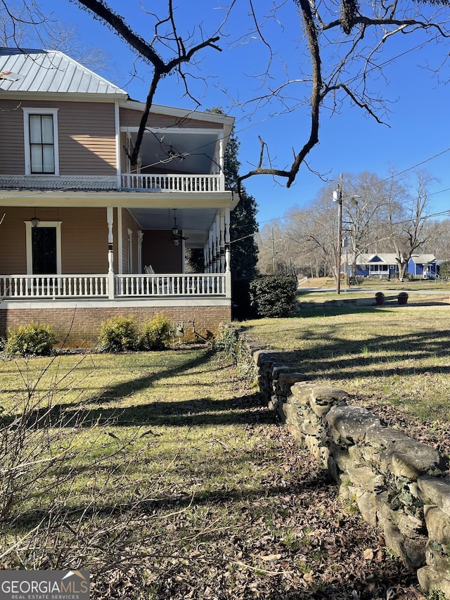 view of property exterior featuring ceiling fan, a lawn, covered porch, and a balcony