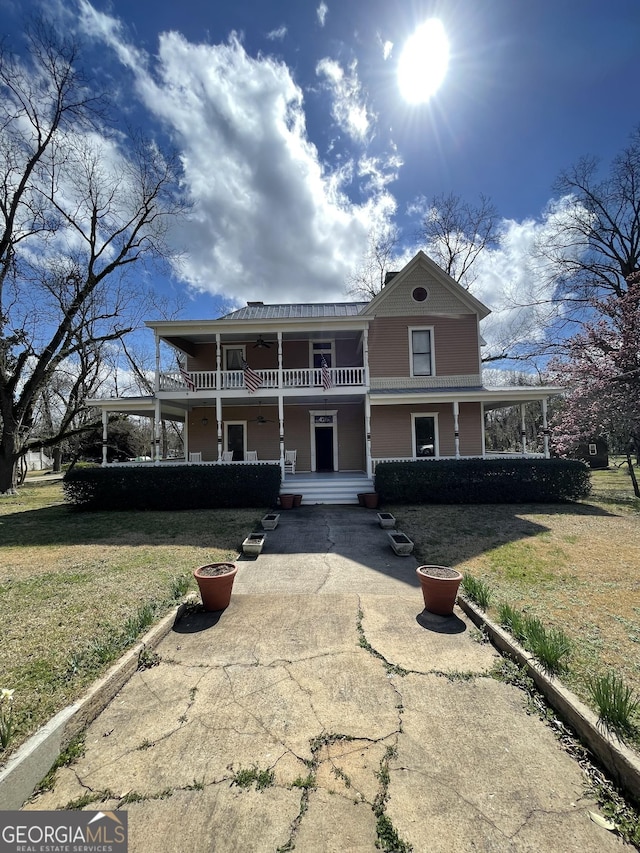 view of front of home with a balcony, a front yard, and a porch