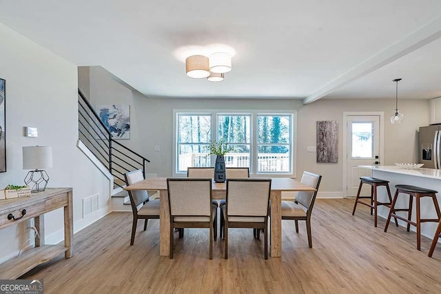 dining room featuring plenty of natural light, light hardwood / wood-style flooring, and beamed ceiling