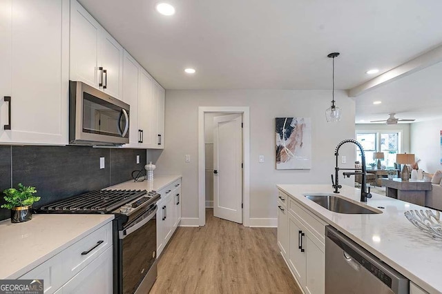 kitchen featuring white cabinetry, ceiling fan, stainless steel appliances, hanging light fixtures, and sink