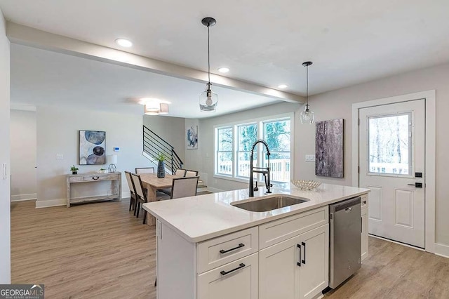 kitchen featuring a center island with sink, hanging light fixtures, stainless steel dishwasher, white cabinets, and sink