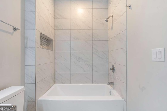 bathroom featuring toilet and tiled shower / bath