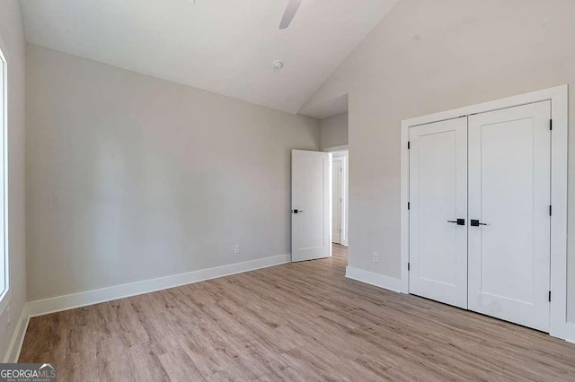 unfurnished bedroom with ceiling fan, vaulted ceiling, light wood-type flooring, and a closet