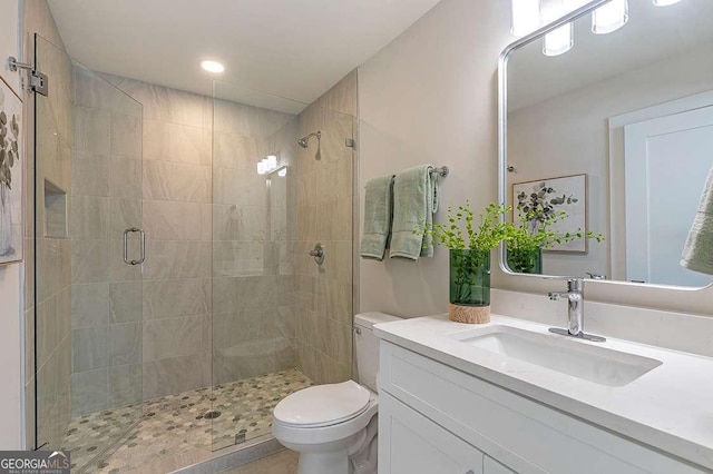 bathroom featuring toilet, a shower with door, and vanity