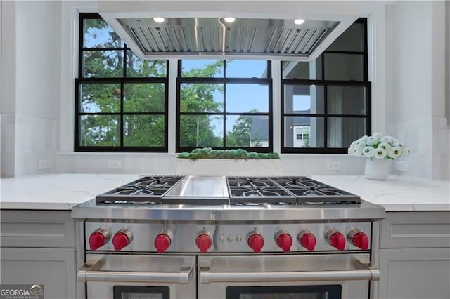 kitchen with light stone countertops, double oven range, and gray cabinets