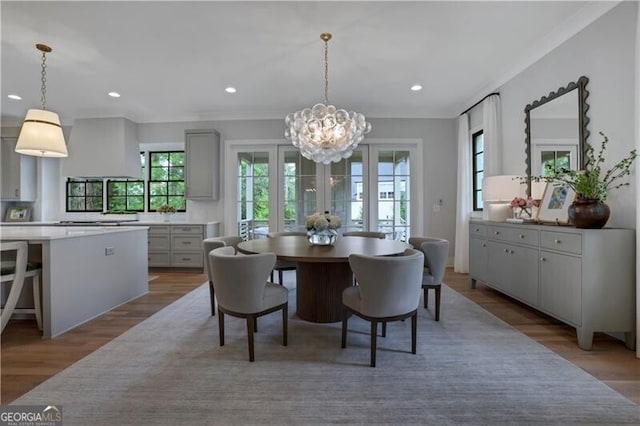 dining space with french doors, hardwood / wood-style flooring, and a notable chandelier