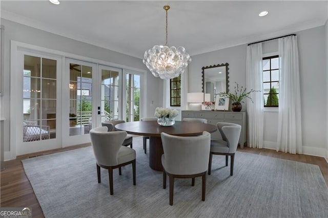 dining room with hardwood / wood-style flooring, an inviting chandelier, and french doors