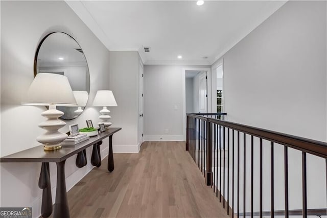 hallway with light wood-type flooring and ornamental molding