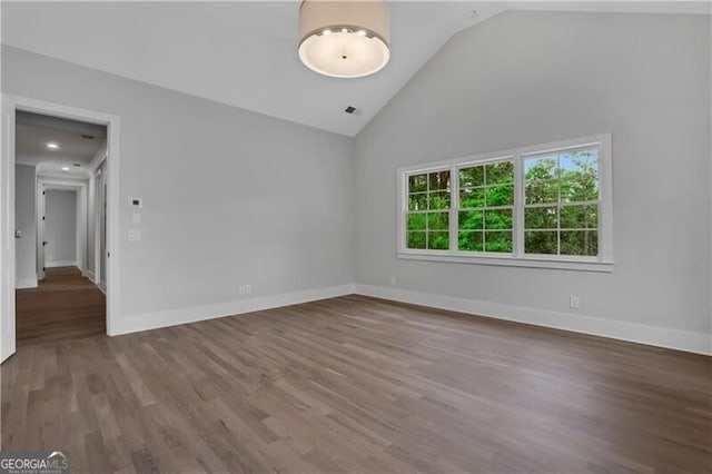 empty room with vaulted ceiling and wood-type flooring