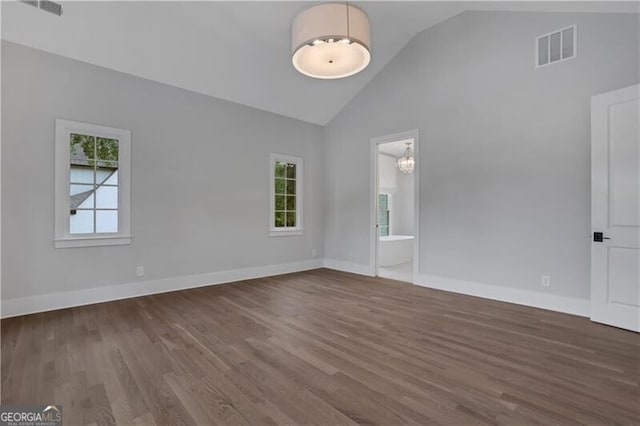 unfurnished room with vaulted ceiling, dark hardwood / wood-style floors, and a notable chandelier