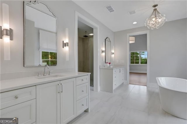 bathroom with a bath, a notable chandelier, and vanity