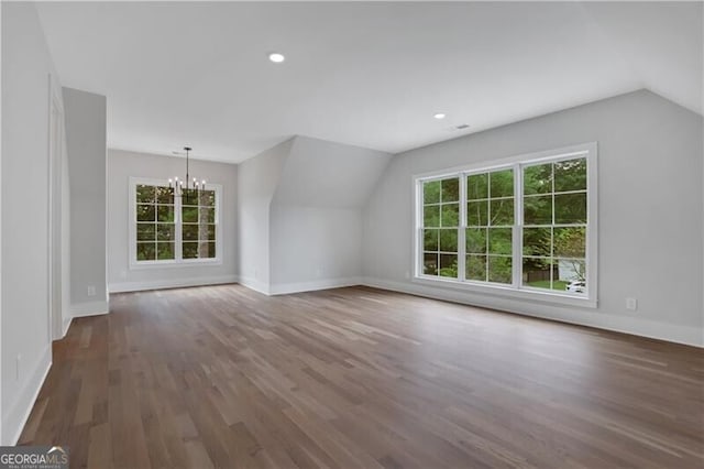 additional living space with dark wood-type flooring, lofted ceiling, and an inviting chandelier