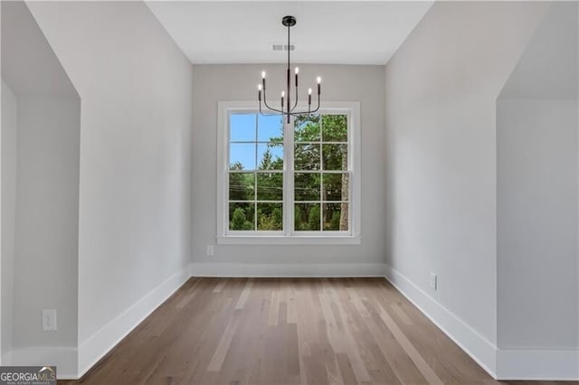 unfurnished dining area with light hardwood / wood-style floors and an inviting chandelier