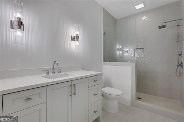 bathroom with toilet, vanity, a tile shower, and tile patterned flooring