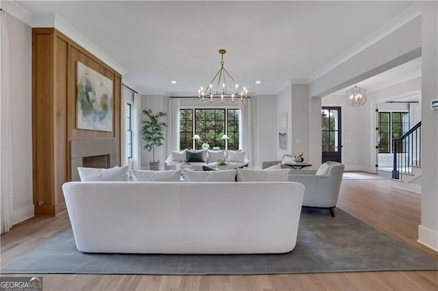 living room with a notable chandelier, ornamental molding, and hardwood / wood-style floors