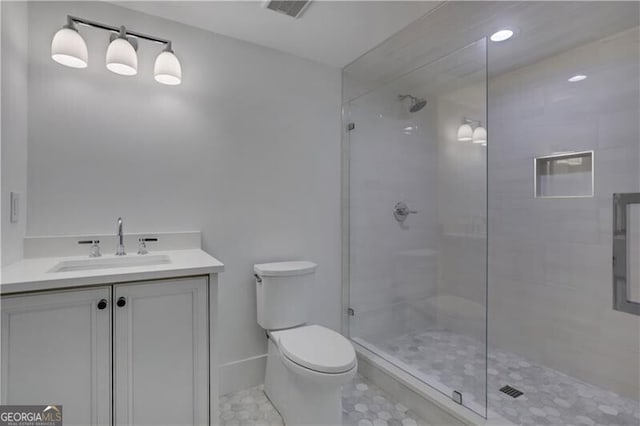 bathroom with toilet, vanity, and a tile shower