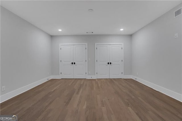 unfurnished bedroom featuring hardwood / wood-style flooring and two closets