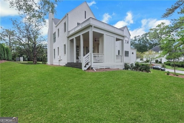 view of side of property with ceiling fan and a yard